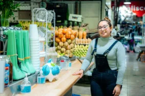 A woman standing in front of a fruit stand
